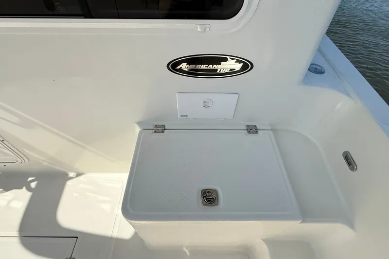 Slide: The Image of American Tug 365 boat deck, 2012 model, featuring storage compartment and logo. - 17
