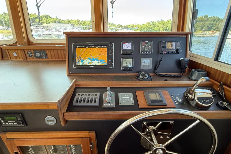 Slide: The Image of American Tug 365 helm with navigation equipment and controls, showcasing a scenic waterway view. - 86