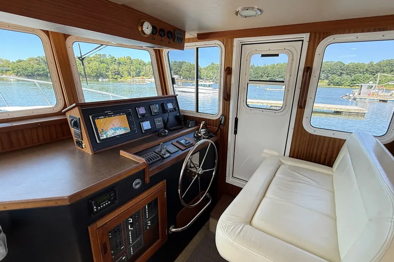 Slide: The Image of Interior of a 2012 American Tug 365, featuring helm and seating with scenic water view. - 83