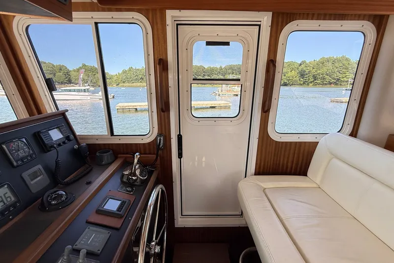 Slide: The Image of Interior view of 2012 American Tug 365, showcasing helm and seating with scenic water view. - 136
