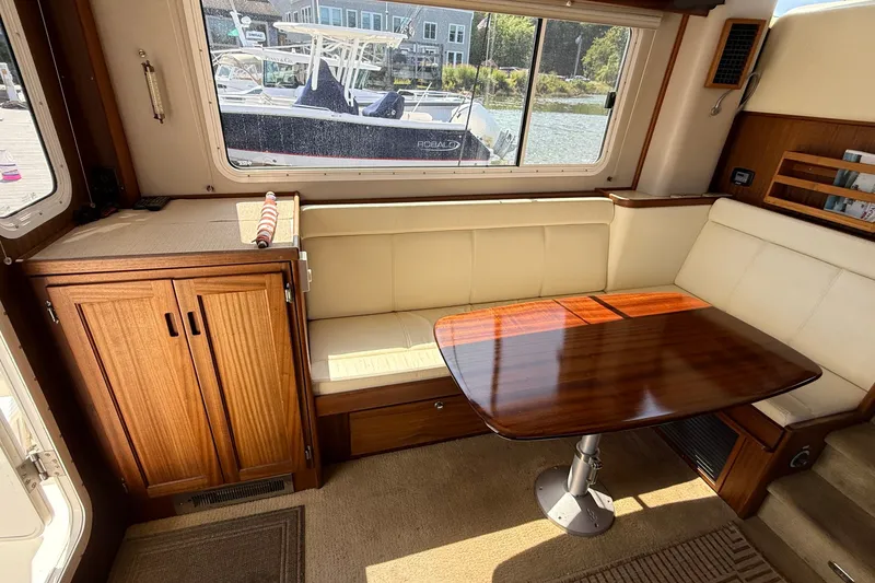 Slide: The Image of Cozy dining area in a 2012 American Tug 365 with wooden table and cream seating. - 58