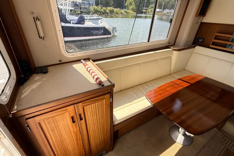 Slide: The Image of Interior of 2012 American Tug 365 with cream seating and wooden table by a window. - 48