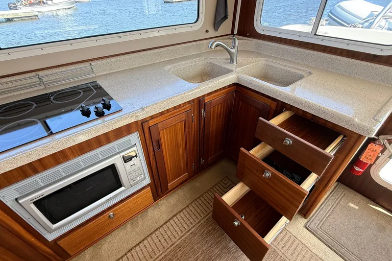 Slide: The Image of Luxurious 2012 American Tug 365 galley with wood cabinetry, dual sinks, and modern appliances. - 56