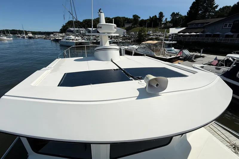 Slide: The Image of 2012 American Tug 365 yacht docked at a marina, showcasing its sleek design and rooftop features. - 11