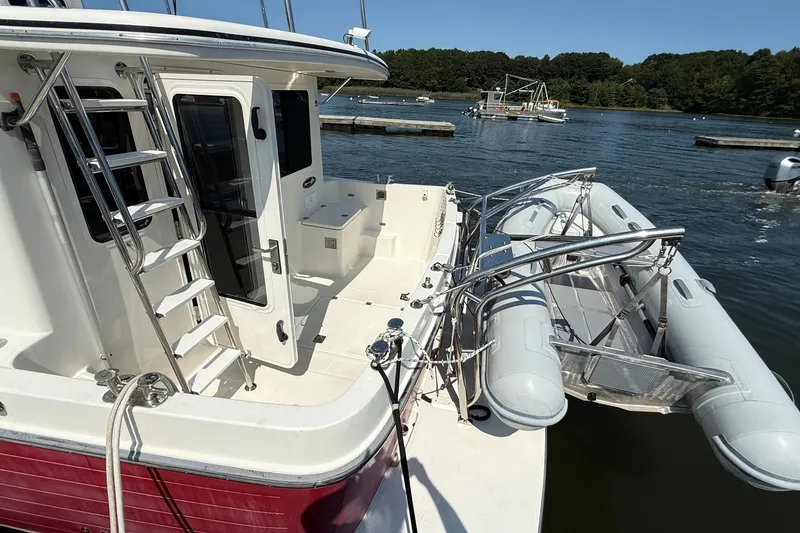 Slide: The Image of American Tug 365 (2012) with inflatable dinghy, docked on a sunny day. - 14