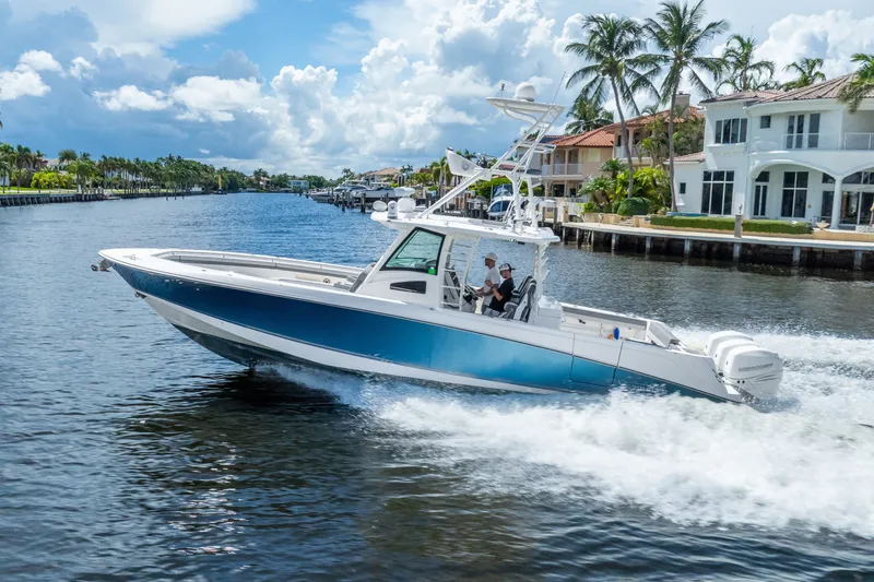 Slide: The Image of 2011 Boston Whaler 370 Outrage cruising on a scenic waterway with palm trees and luxury homes. - 14