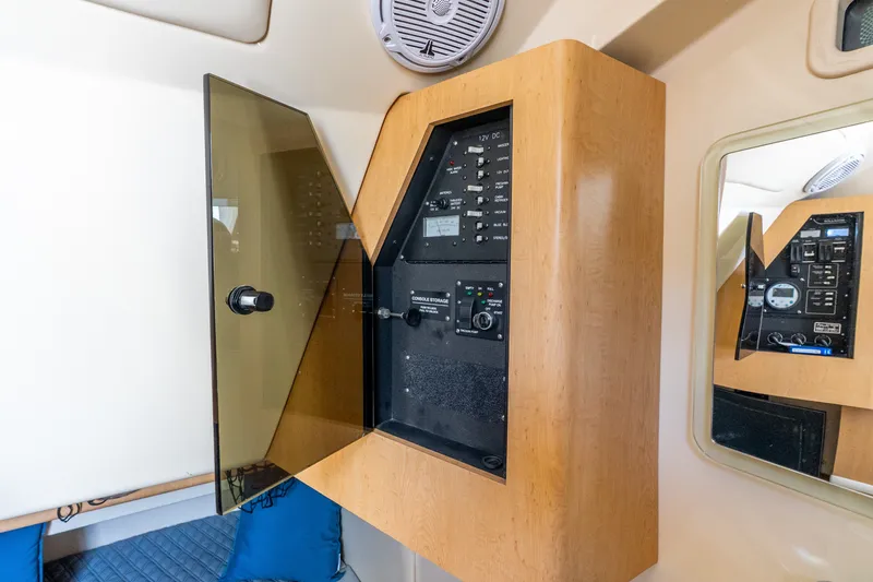 Slide: The Image of 2011 Boston Whaler 370 Outrage electrical panel with wooden cabinet and mirrored reflection. - 40