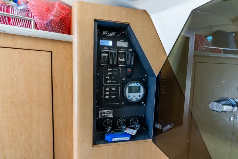 Slide: The Image of Control panel inside 2011 Boston Whaler 370 Outrage boat, featuring switches and a digital display. - 39