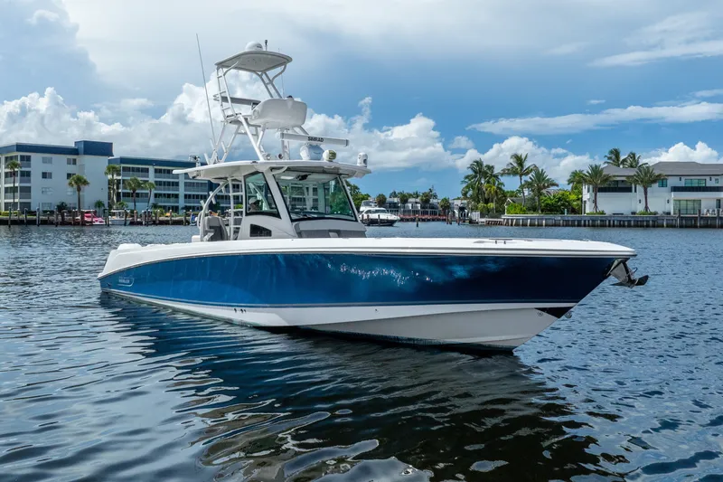 The Image of 2011 Boston Whaler 370 Outrage boat on calm water, with buildings and palm trees in background. - 0