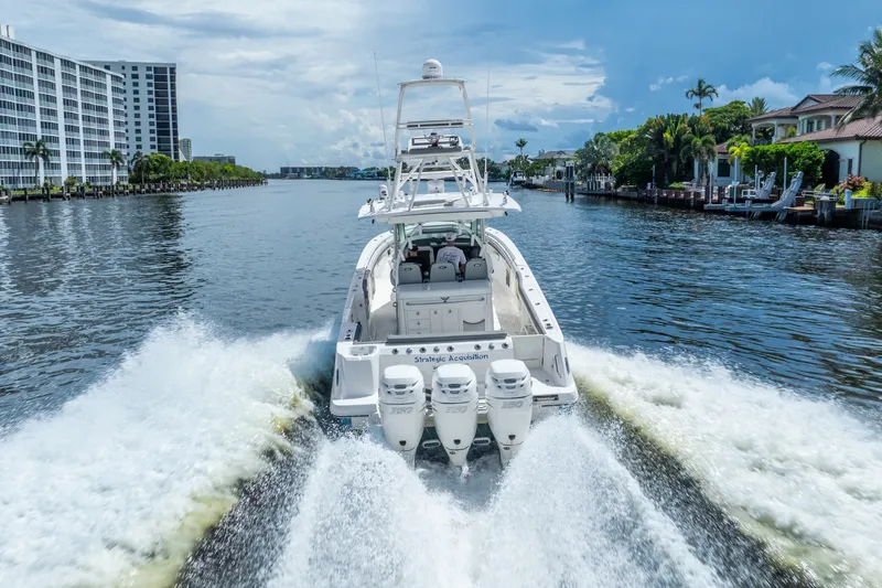 Slide: The Image of 2011 Boston Whaler 370 Outrage cruising on a scenic waterway, surrounded by buildings and palm trees. - 17