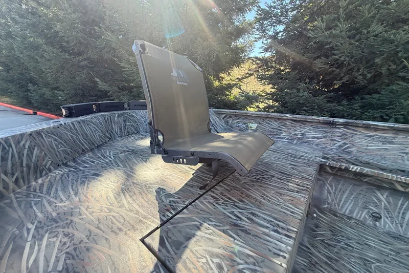 Slide: The Image of 2027 Tracker Grizzly 1553 Timber boat with camo interior and foldable seat in sunlight. - 14