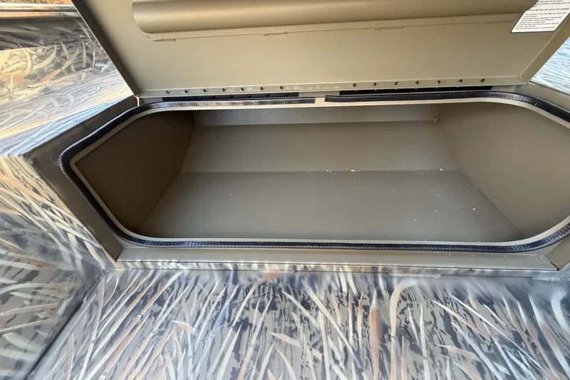 Slide: The Image of Open storage compartment in 2027 Tracker Grizzly 1553 Timber boat, featuring camo design. - 15