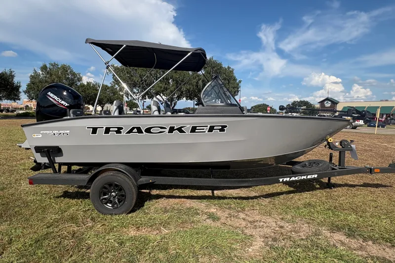 Slide: The Image of 2027 Tracker Pro Guide V-175 Combo boat on trailer, parked on grass under blue sky. - 25