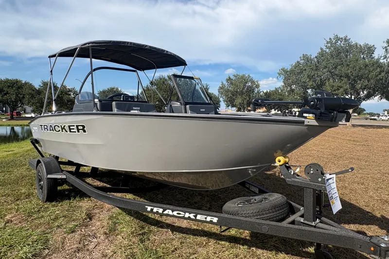 Slide: The Image of 2027 Tracker Pro Guide V-175 Combo boat on trailer, parked on grass under clear sky. - 26