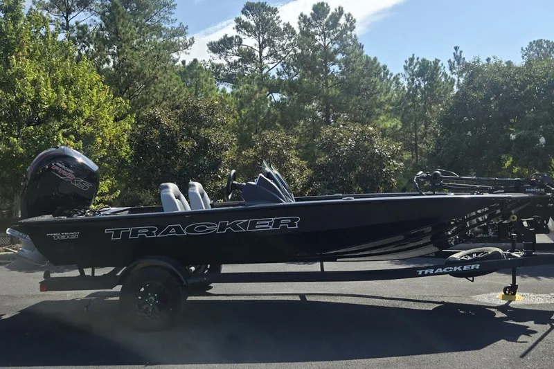 The Image of 2027 Tracker Pro Team 195 boat on trailer, parked outdoors with trees in background. - 0