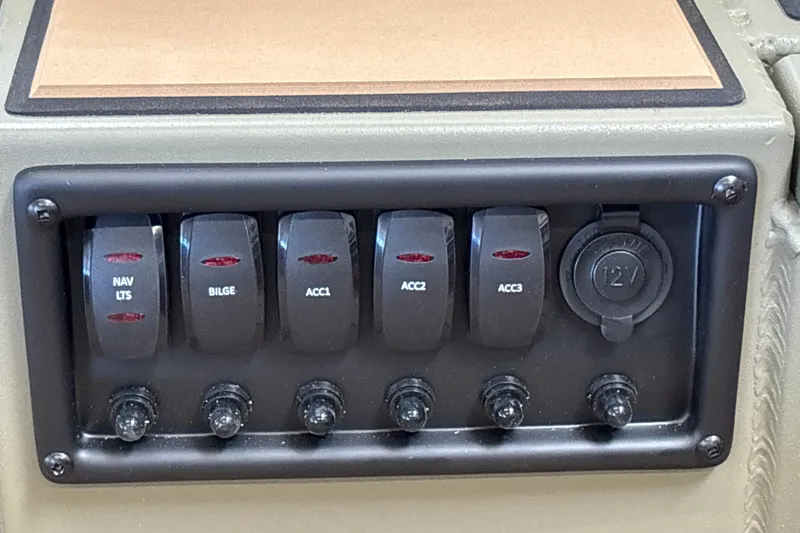 Slide: The Image of Control panel of 2027 Tracker Grizzly 1553 Timber with switches and 12V outlet. - 18