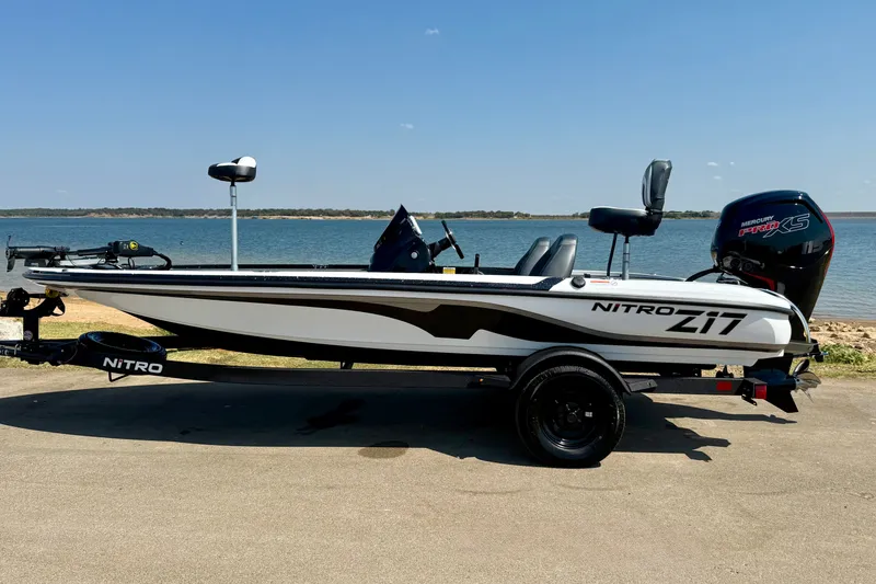 Slide: The Image of 2027 Nitro Z17 boat on trailer by a lake, clear sky background. - 15