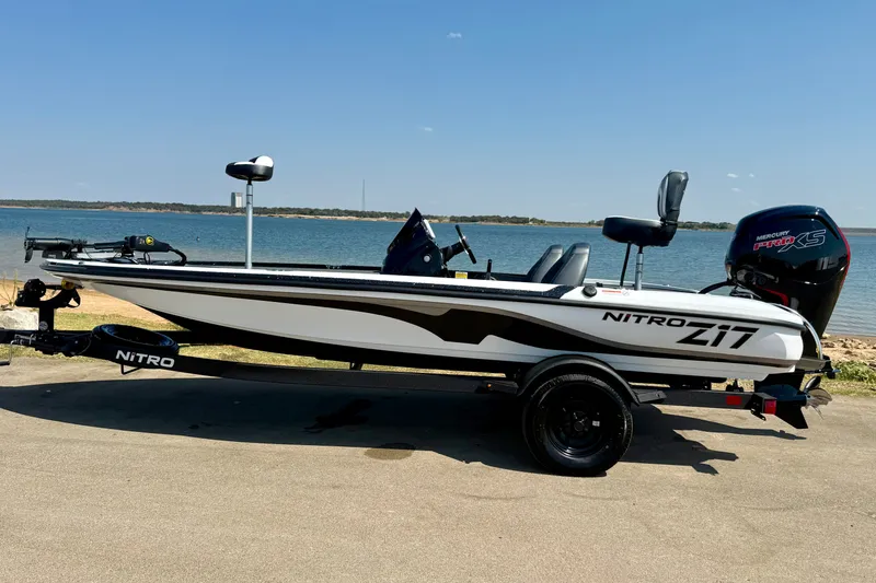Slide: The Image of 2027 Nitro Z17 boat with Mercury engine, parked by a serene lake under a clear blue sky. - 14