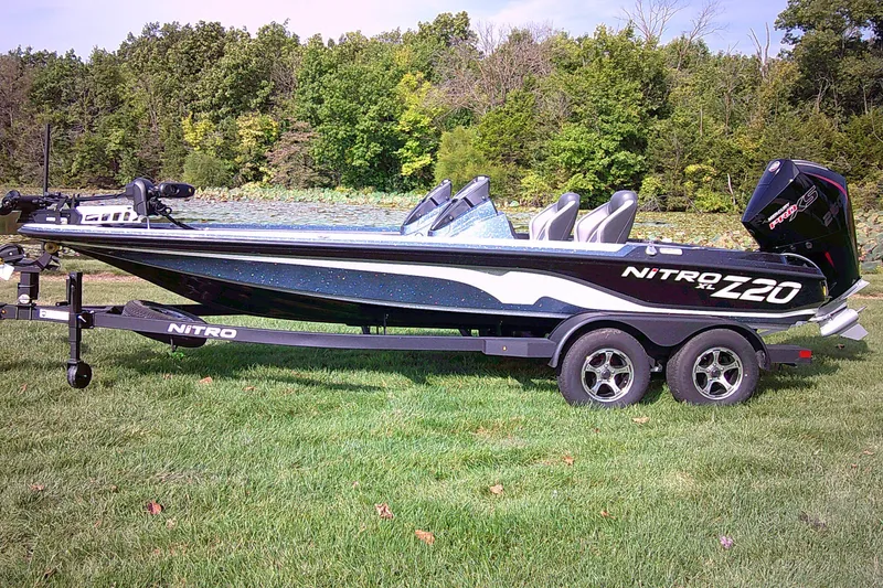 The Image of 2025 Nitro Z20 XL Pro boat on trailer, parked on grass with forest background. - 0
