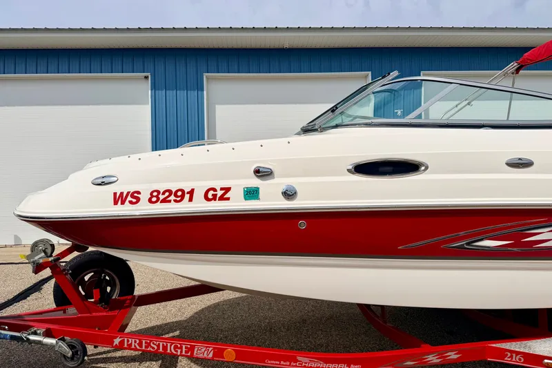 Slide: The Image of 2006 Chaparral Sunesta 216 boat on trailer, red and white design, parked near blue building. - 12