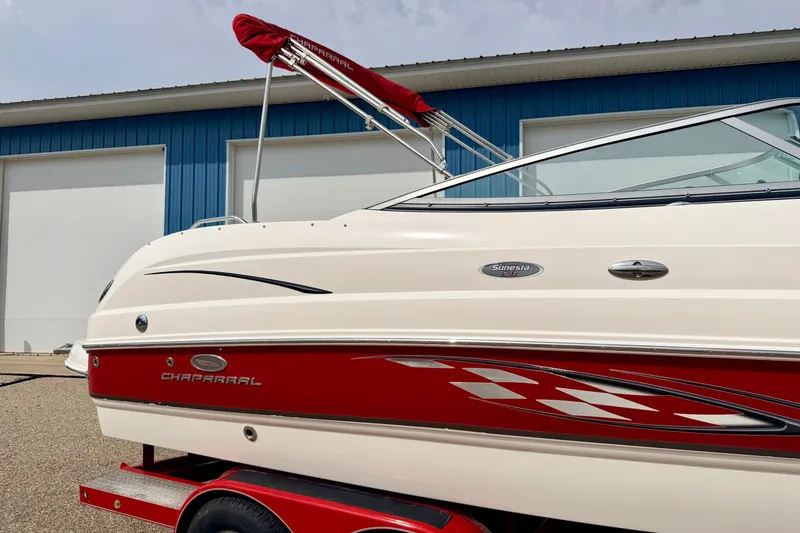 Slide: The Image of 2006 Chaparral Sunesta 216 boat with red accents, parked near blue building. - 7