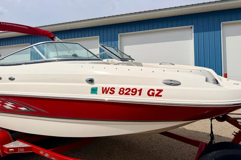 Slide: The Image of 2006 Chaparral Sunesta 216 boat with red and white design, parked near blue building. - 6