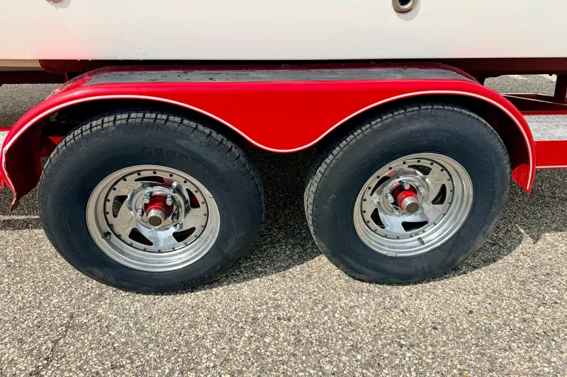 Slide: The Image of Red trailer wheels of a 2006 Chaparral Sunesta 216 boat on pavement. - 87