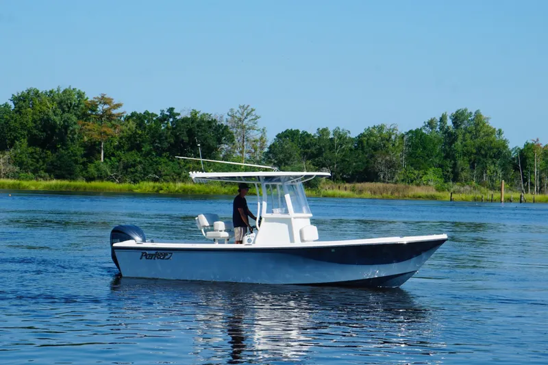 The Image of 2023 Parker 23SE Center Console boat on a calm lake with lush green trees. - 0