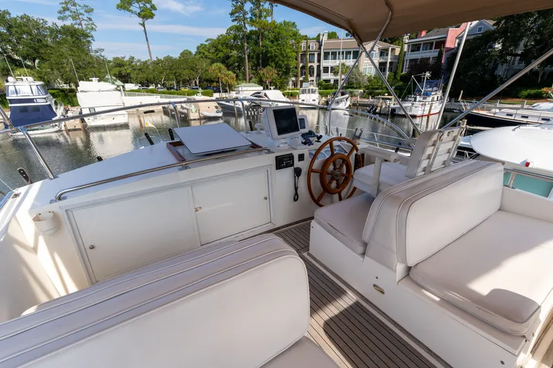 Slide: The Image of Grand Banks 46 Classic 1998 yacht helm with white seating and wooden steering wheel. - 75