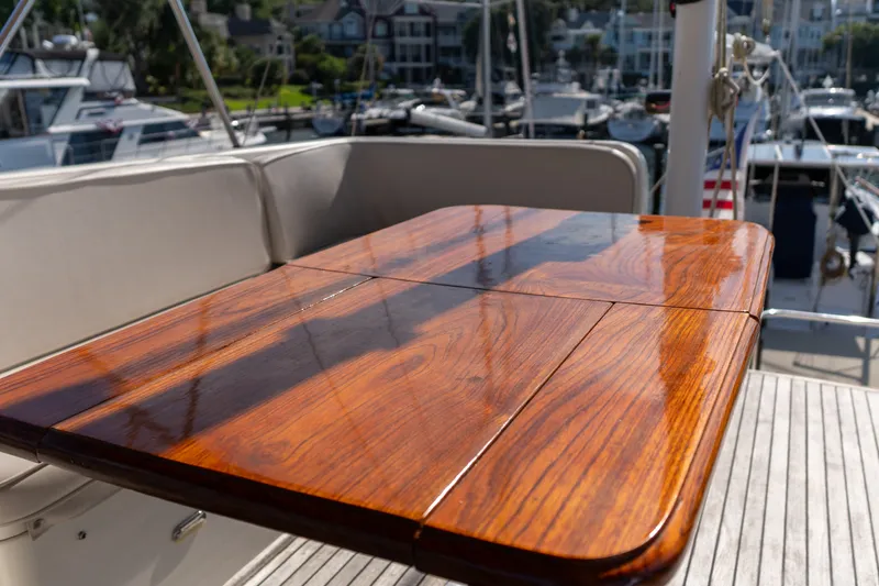 Slide: The Image of Polished wooden table on 1998 Grand Banks 46 Classic yacht deck, marina background. - 85