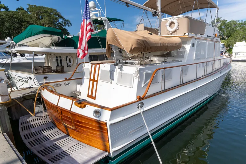 Slide: The Image of 1998 Grand Banks 46 Classic yacht docked, featuring elegant woodwork and American flag. - 8