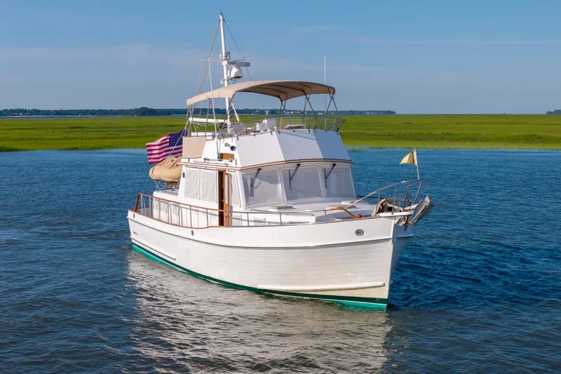 Slide: The Image of 1998 Grand Banks 46 Classic yacht cruising on calm waters with scenic green shoreline. - 100