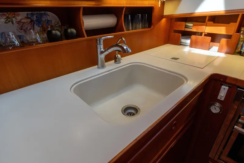 Slide: The Image of Kitchen sink area in a 1998 Grand Banks 46 Classic yacht, featuring wooden cabinetry. - 28