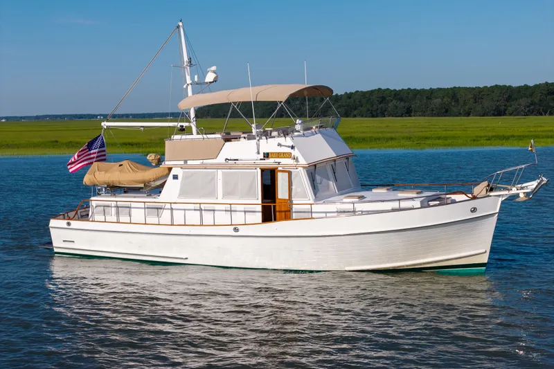 Slide: The Image of 1998 Grand Banks 46 Classic yacht cruising on a serene waterway under a clear blue sky. - 99