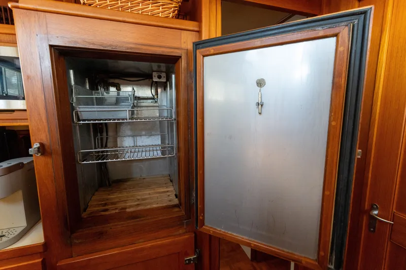 Slide: The Image of Wooden cabinet with open stainless steel interior, shelves inside, on a 1998 Grand Banks 46 Classic. - 26