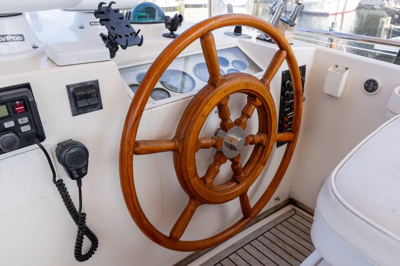 Slide: The Image of Wooden helm of a 1998 Grand Banks 46 Classic yacht, featuring navigation controls. - 79