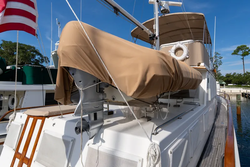 Slide: The Image of 1998 Grand Banks 46 Classic yacht docked, featuring covered equipment and American flag. - 71