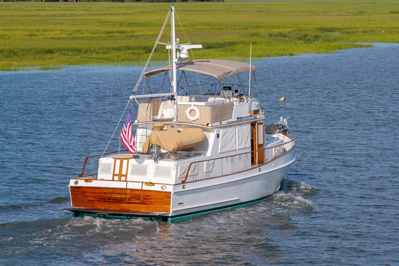 Slide: The Image of Grand Banks 46 Classic von 1998 auf ruhigem Wasser, mit amerikanischer Flagge und grünem Ufer. - 7
