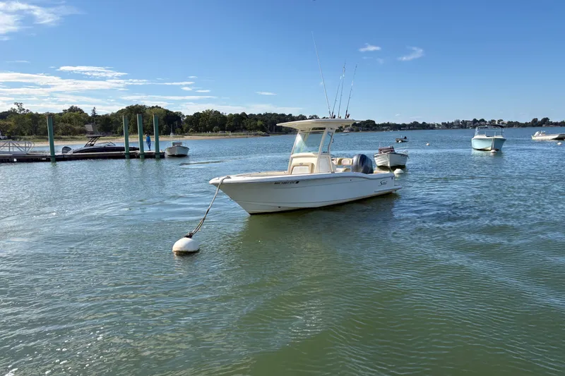 The Image of 2014 Scout 225 XSF boat moored on a calm lake under a clear blue sky. - 0