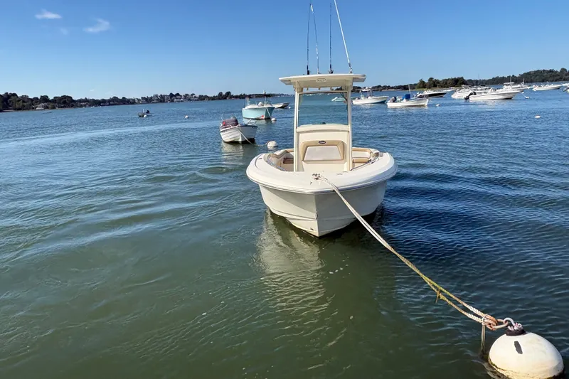 Slide: The Image of 2014 Scout 225 XSF boat moored on calm water with other boats nearby. - 3