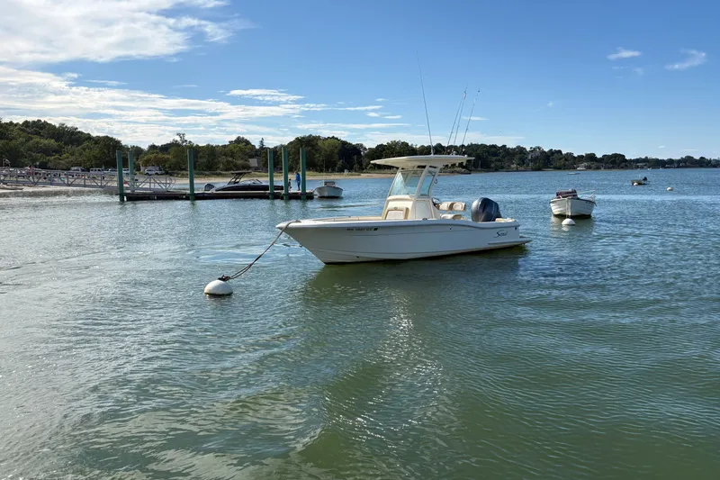 Slide: The Image of 2014 Scout 225 XSF boat moored on calm water near a dock under a clear sky. - 1