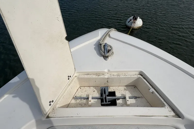 Slide: The Image of 2014 Scout 225 XSF boat anchor compartment with open hatch and rope on water. - 31