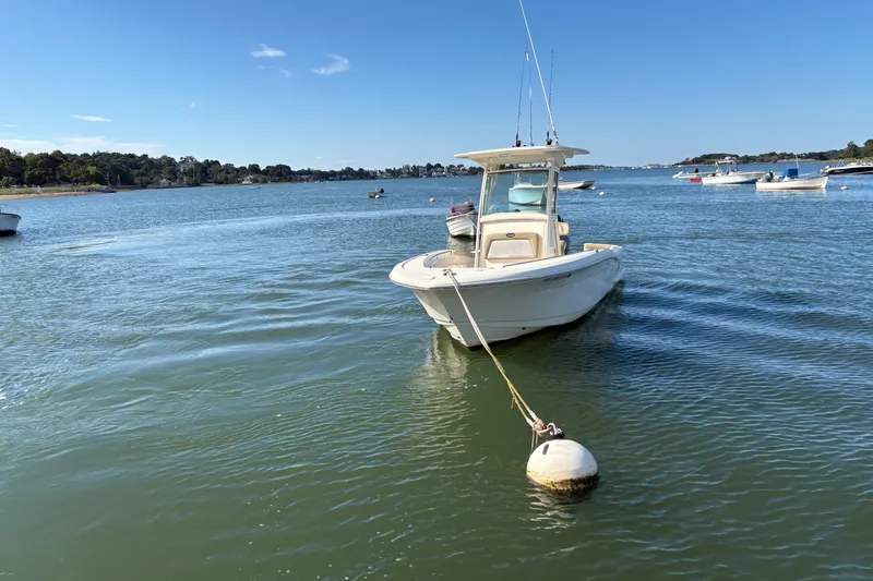Slide: The Image of 2014 Scout 225 XSF boat moored on calm water under clear blue sky. - 2