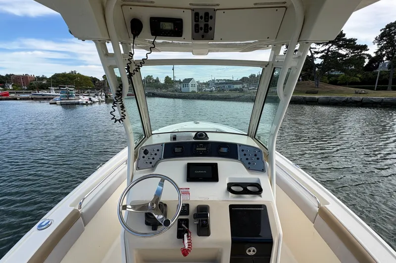 Slide: The Image of 2014 Scout 225 XSF boat dashboard with steering wheel and navigation equipment on calm water. - 20