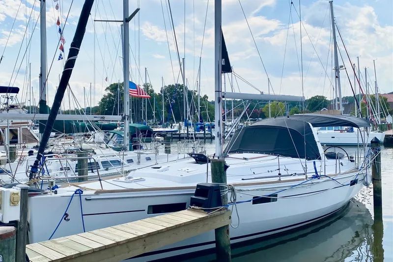 The Image of 2016 Beneteau Oceanis 41 sailboat docked at a marina under a partly cloudy sky. - 1