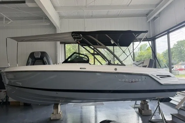 Slide: The Image of 2027 Monterey Elite 23 SD boat displayed indoors with canopy and sleek design. - 14