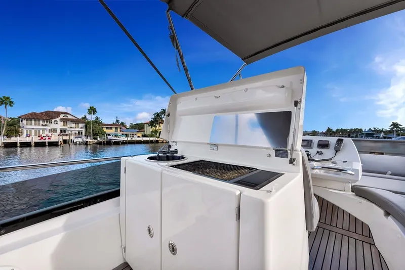 Slide: The Image of Luxury yacht Prestige 550 (2013) with outdoor kitchen, docked by waterfront homes. - 43