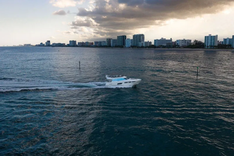 Slide: The Image of Prestige 550 yacht cruising near city skyline under cloudy sky, 2013 model. - 23