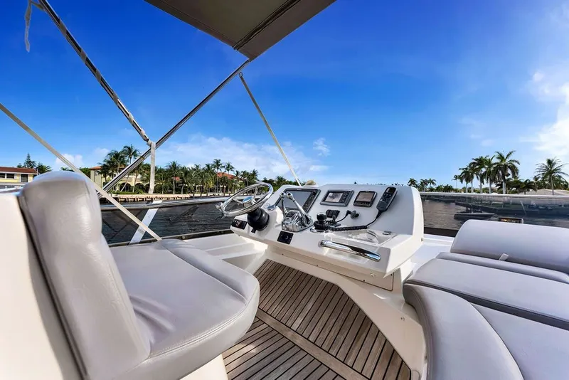 Slide: The Image of Prestige 550 yacht helm with modern controls, luxurious seating, and scenic waterfront view. - 38