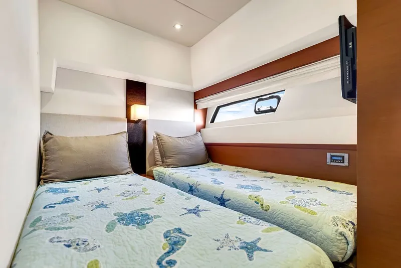 Slide: The Image of Twin beds in a 2013 Prestige 550 yacht cabin with nautical-themed bedding. - 75